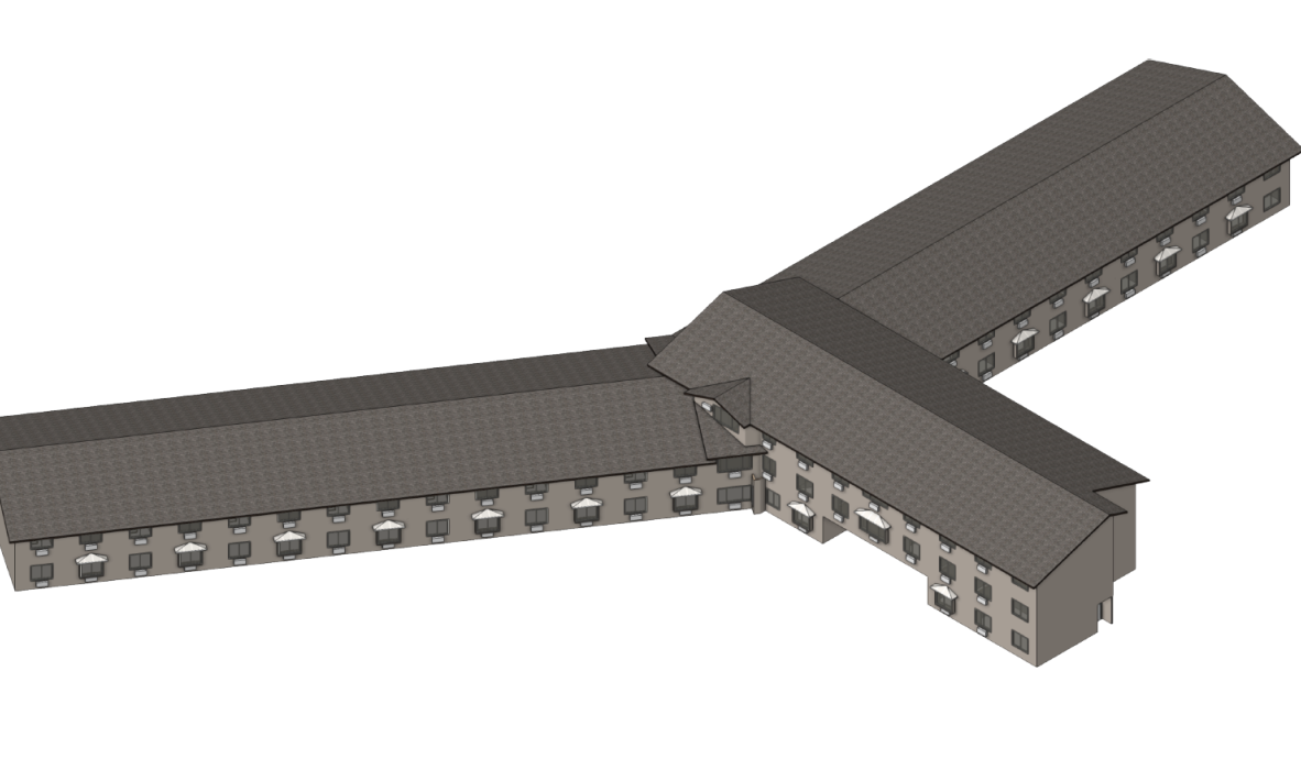Aerial view of a large, L-shaped building with a dark roof and multiple windows on each side. The structure has two wings extending outward, forming a V-shape. The design appears uniform and symmetrical.