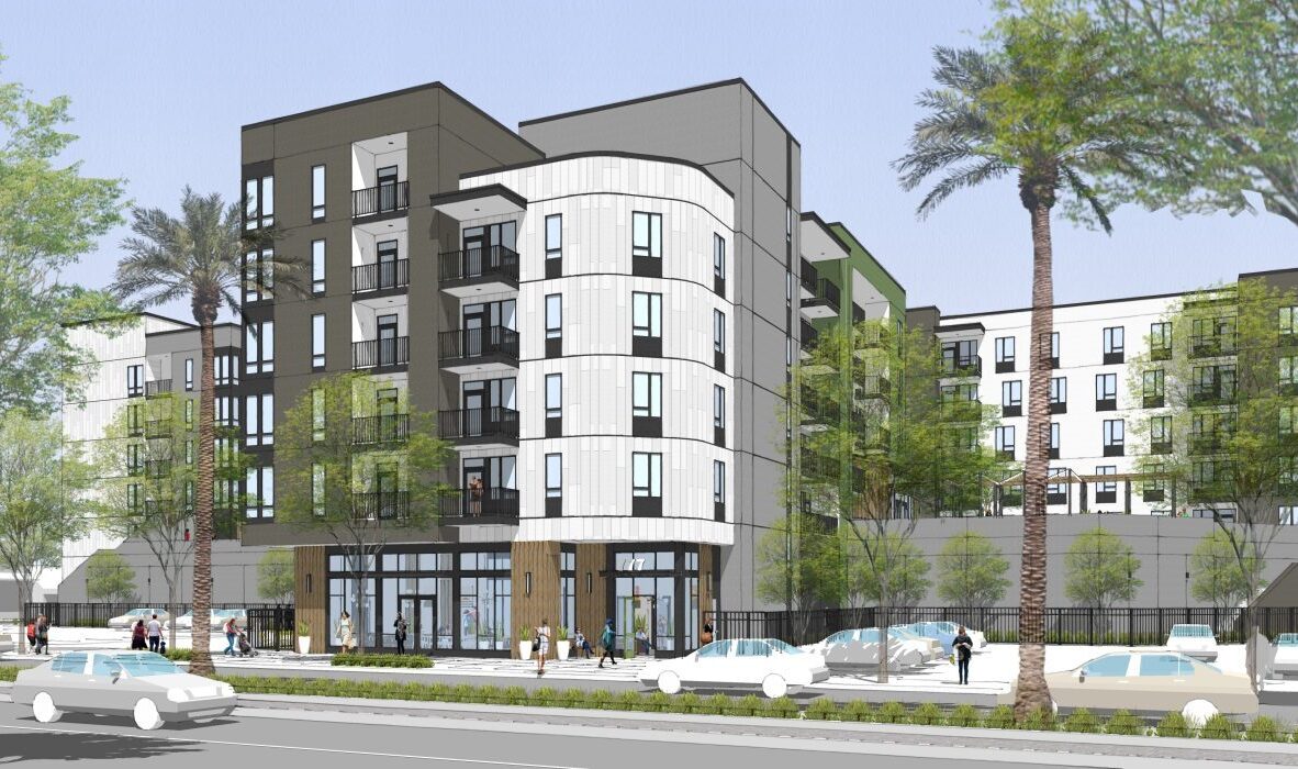 A modern multi-story apartment building with balconies, large windows, and surrounding trees. Pedestrians walk along the sidewalk while cars pass by on the street in the foreground.
