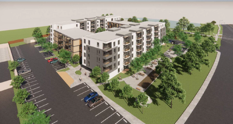 Aerial view of a modern apartment complex surrounded by trees. The buildings have a mix of white and dark facades, with balconies visible. A parking lot with cars is in the foreground, and a landscaped courtyard is in the center.